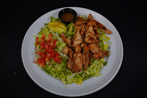 Plate of chicken salad with lettuce, tomatoes, and avocado