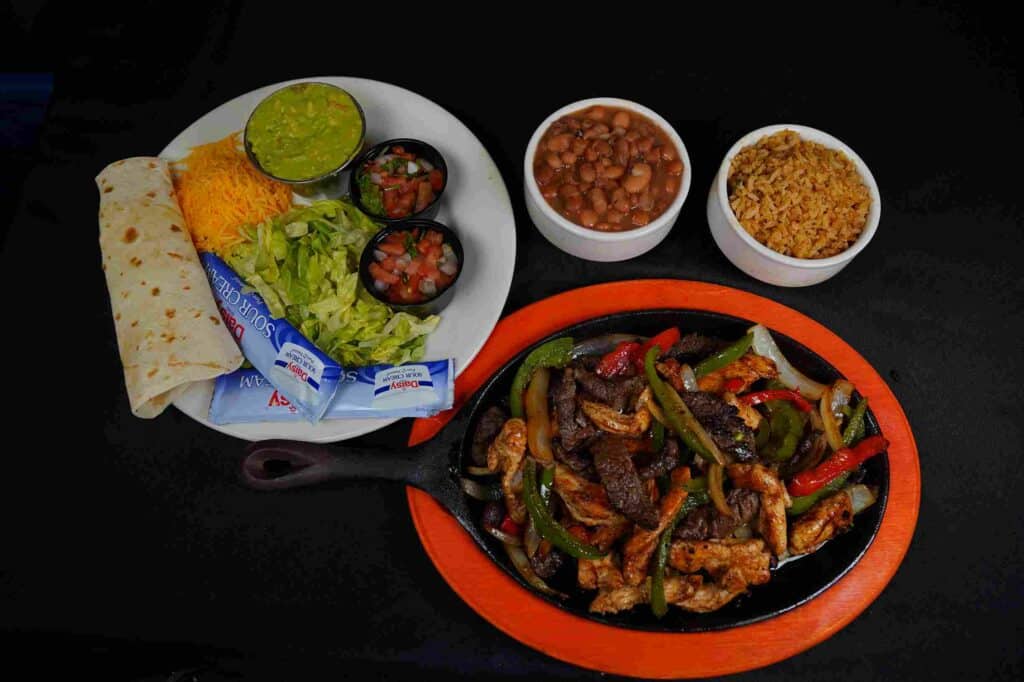 Plate of fajitas, rice, beans, guacamole, and tortillas