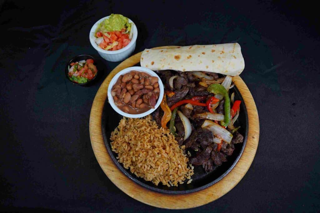 Plate of beef fajitas, rice, beans, and a tortilla