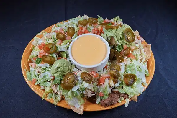 Plate of nachos with guacamole, jalapenos, and cheese