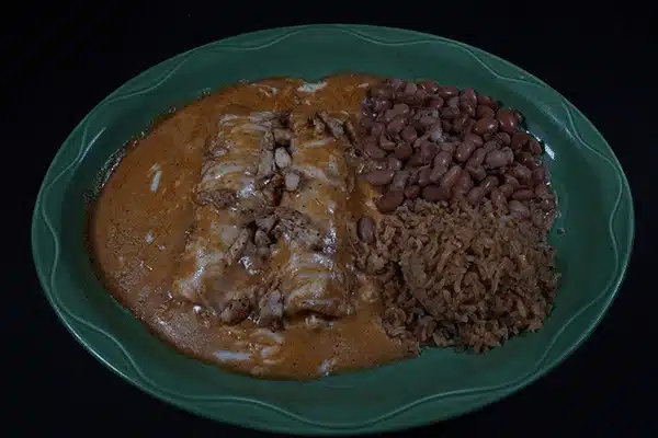Plate of Mexican food with enchiladas, rice, and beans
