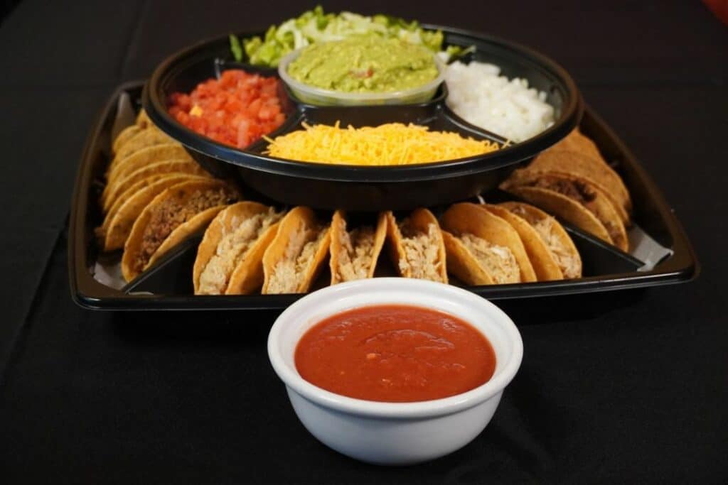 Variety of tacos on a tray topped with vegetables and sauces