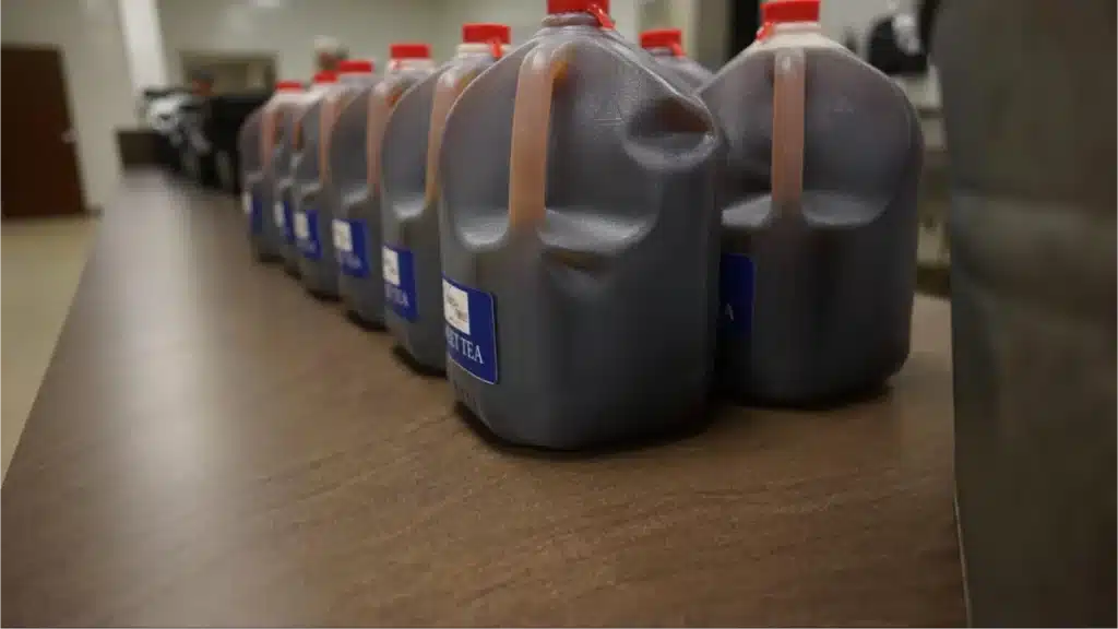 Row of sweet tea jugs on table.