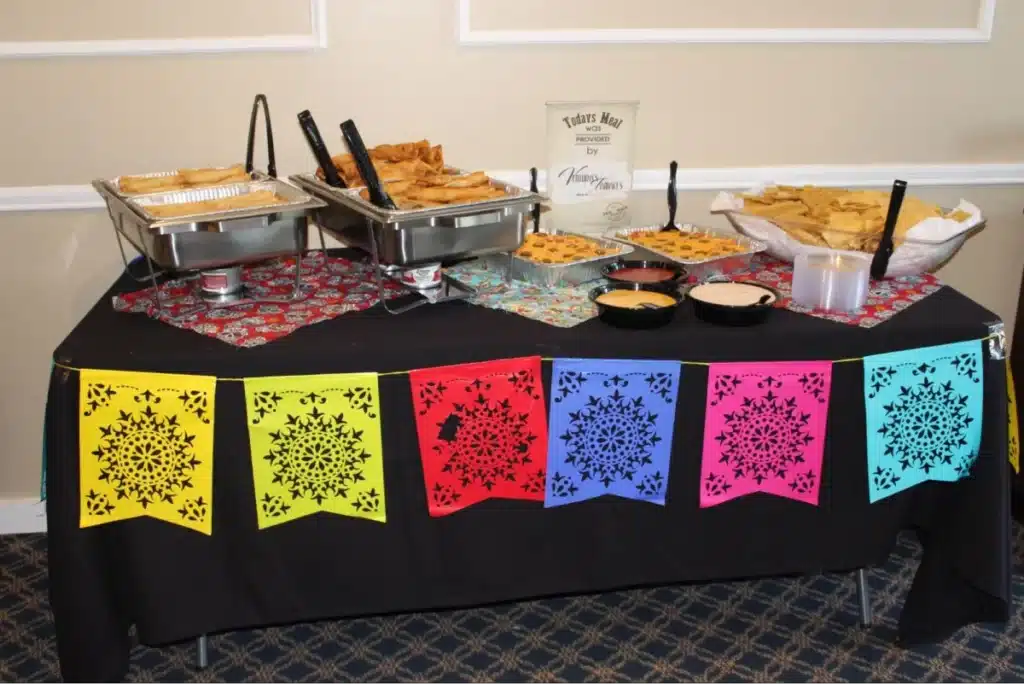 A buffet table with Mexican-themed decorations and various dishes.