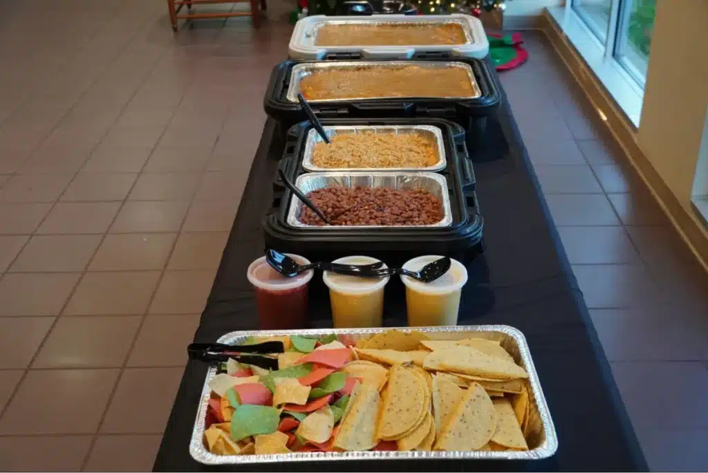 A buffet table with various trays of Mexican food and colorful taco shells.