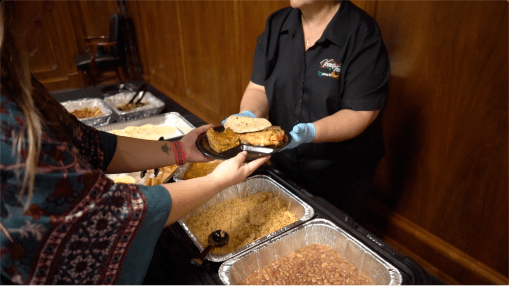 Catering staff serving food from buffet trays.