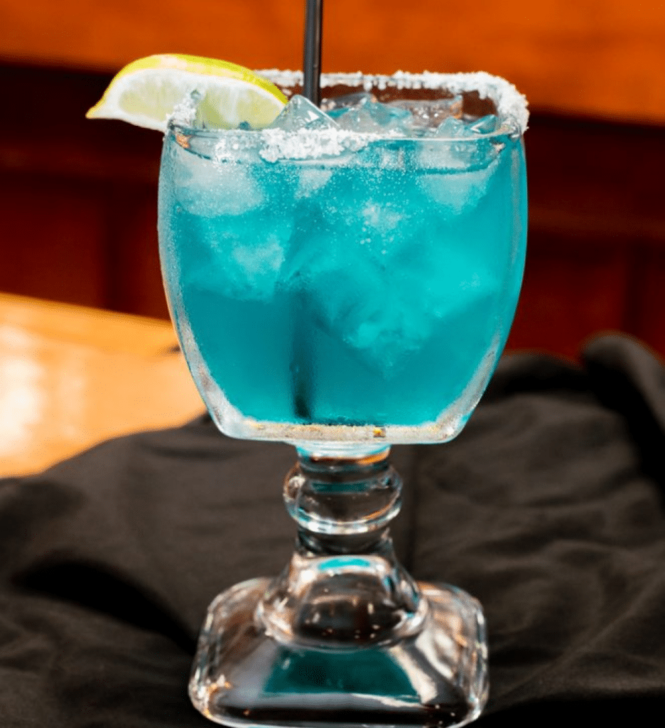 Blue margarita with lime garnish.