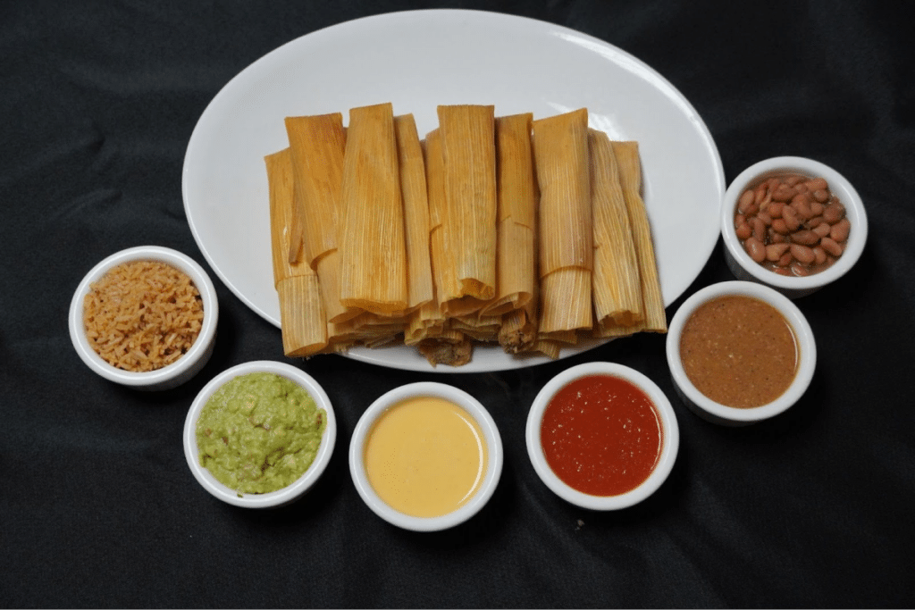 Tamales served with various sauces, beans, rice, and guacamole.